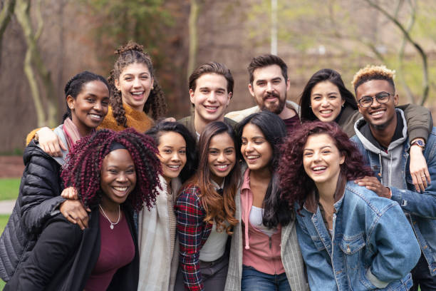adaptation_culturelle A large sized group of university-aged students, both male and female, are standing out on the campus lawn and smiling into the camera in this educational portrait.They are carefree.